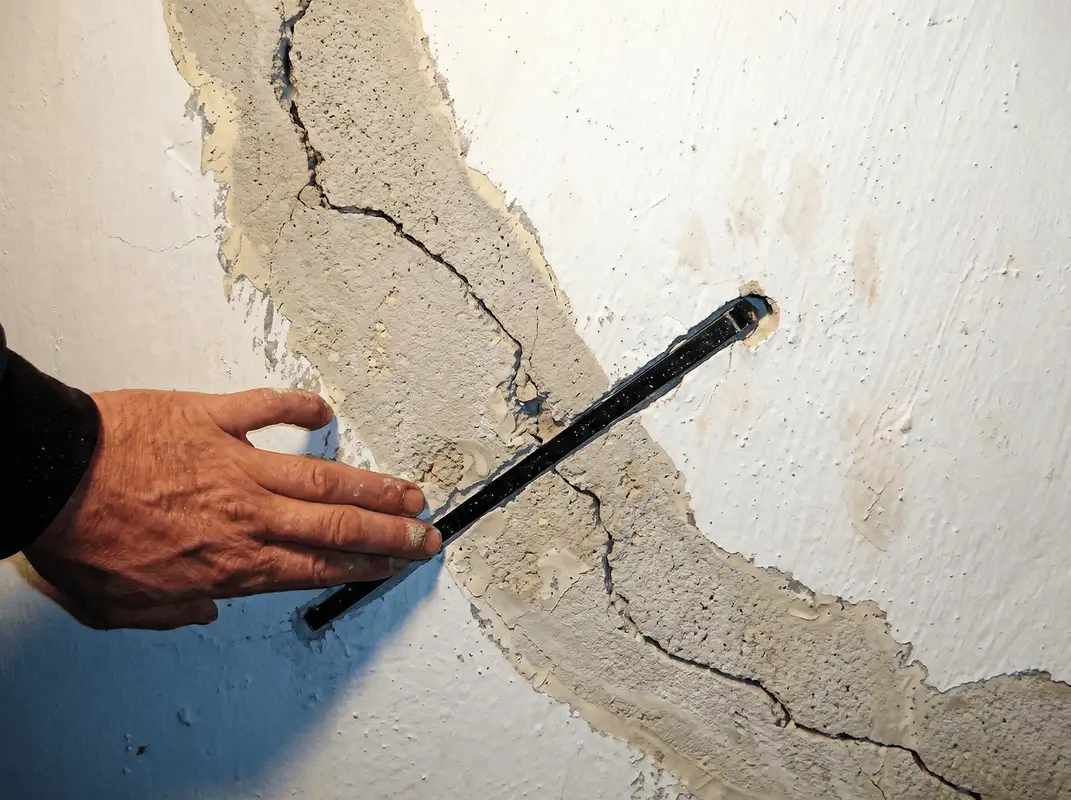 A wall with a large crack is being inspected by a professional in Minneapolis, MN